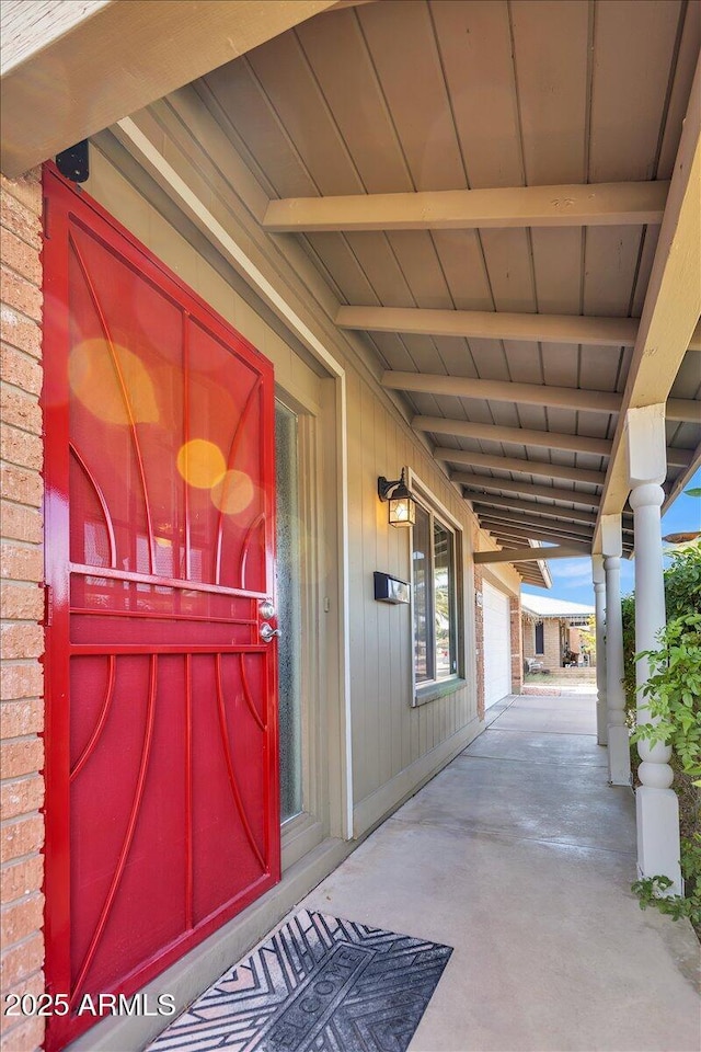 property entrance featuring a porch and brick siding