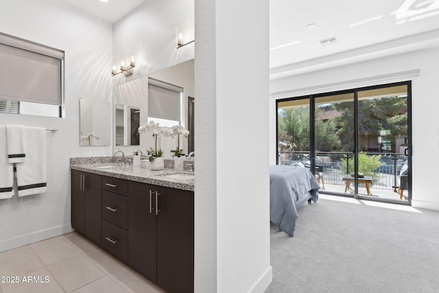 ensuite bathroom with a sink, baseboards, double vanity, and visible vents