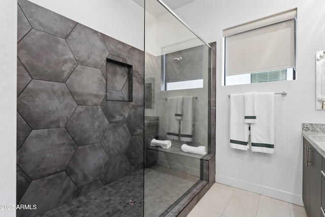 full bath with vanity, baseboards, a walk in shower, and tile patterned flooring