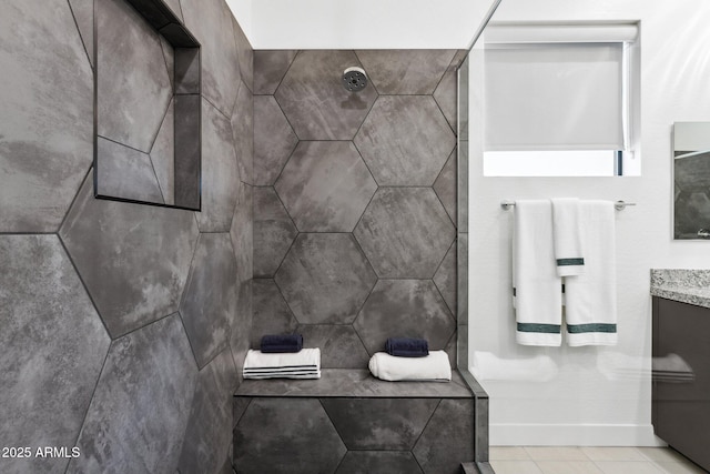 full bathroom with baseboards, a tile shower, tile patterned flooring, and vanity