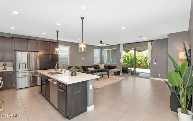 kitchen with a kitchen island with sink, sink, stainless steel appliances, and dark brown cabinetry