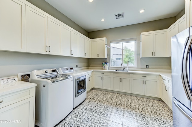 laundry area with cabinets, washer and clothes dryer, and sink