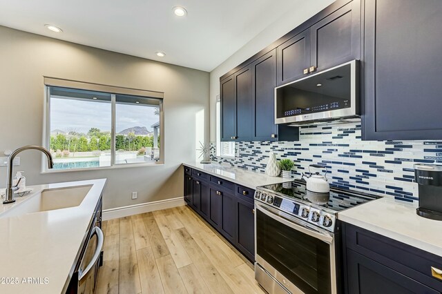 kitchen with sink, stainless steel appliances, tasteful backsplash, and light wood-type flooring