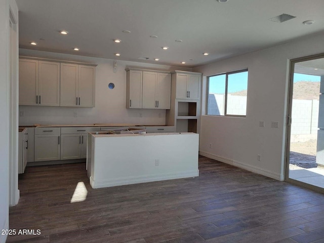 kitchen with dark wood-type flooring, a center island, and a healthy amount of sunlight