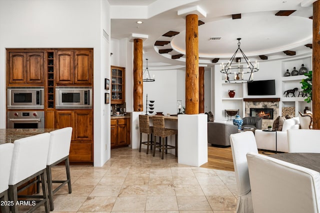 7025 E Ashler Hills Dr, Scottsdale, AZ 85266 - kitchen with stainless steel appliances, open floor plan, a chandelier, built in features, and a lit fireplace