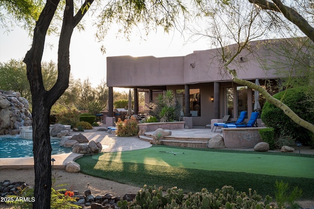 7025 E Ashler Hills Dr, Scottsdale, AZ 85266 - back of property featuring a putting area, a patio, stucco siding, and an outdoor pool