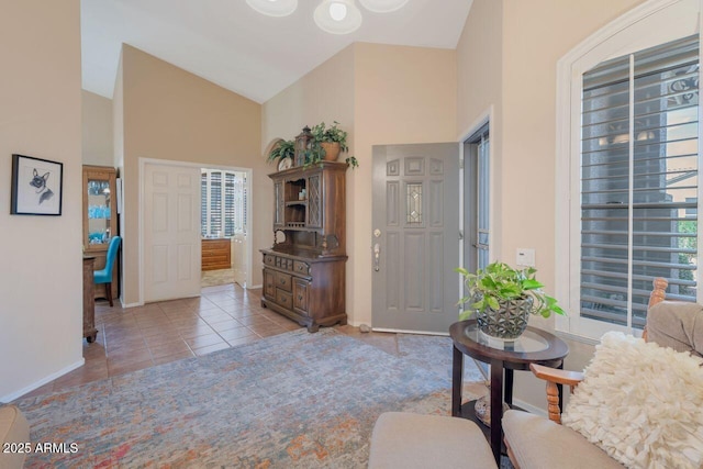 entryway featuring a healthy amount of sunlight, high vaulted ceiling, baseboards, and light tile patterned flooring