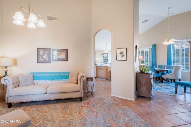 living area featuring light tile patterned floors, baseboards, visible vents, arched walkways, and high vaulted ceiling