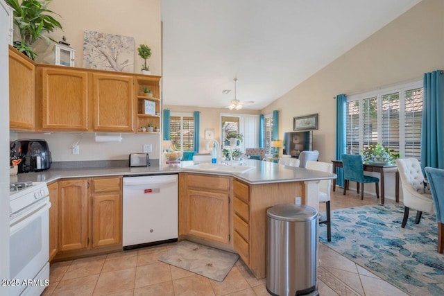 kitchen featuring a peninsula, white appliances, a sink, light countertops, and a wealth of natural light