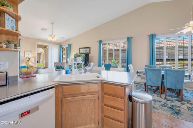 kitchen featuring a ceiling fan, vaulted ceiling, white dishwasher, a sink, and a peninsula