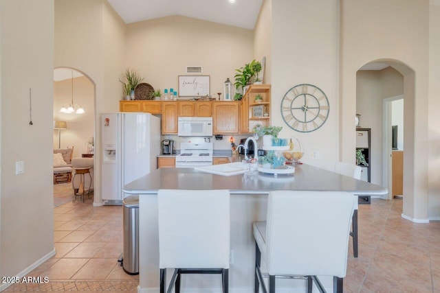 kitchen with high vaulted ceiling, white appliances, light countertops, and a kitchen bar