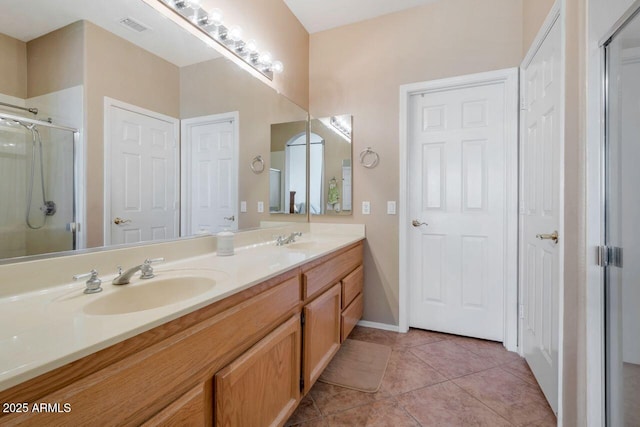 full bath with a shower stall, double vanity, a sink, and tile patterned floors