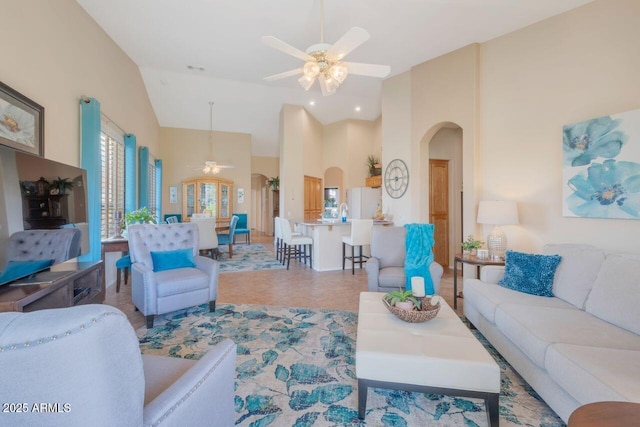 tiled living area with arched walkways, high vaulted ceiling, and a ceiling fan