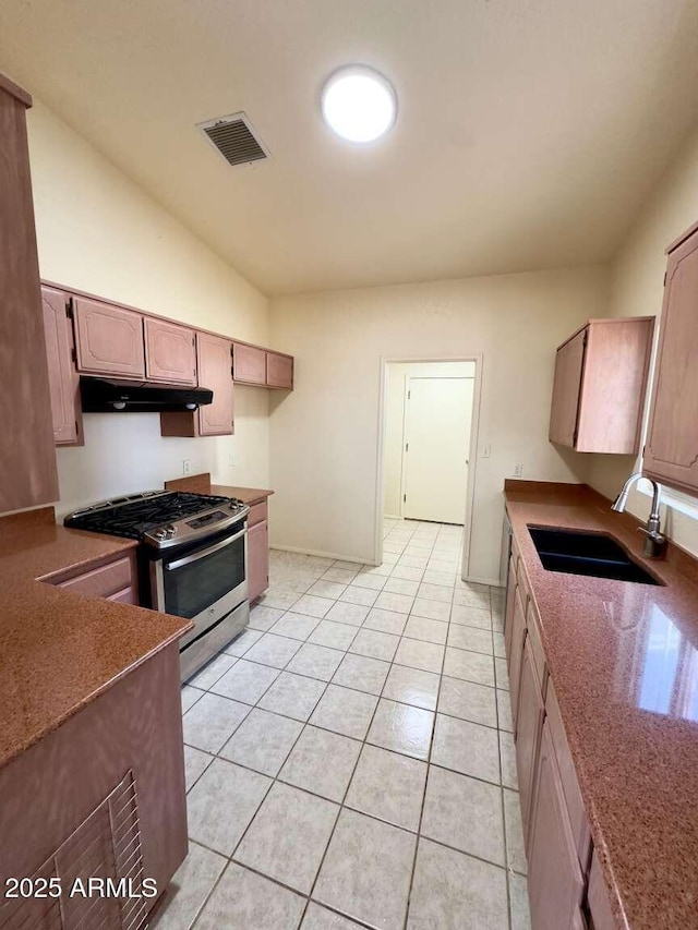 kitchen featuring stainless steel gas stove, light tile patterned floors, visible vents, under cabinet range hood, and a sink