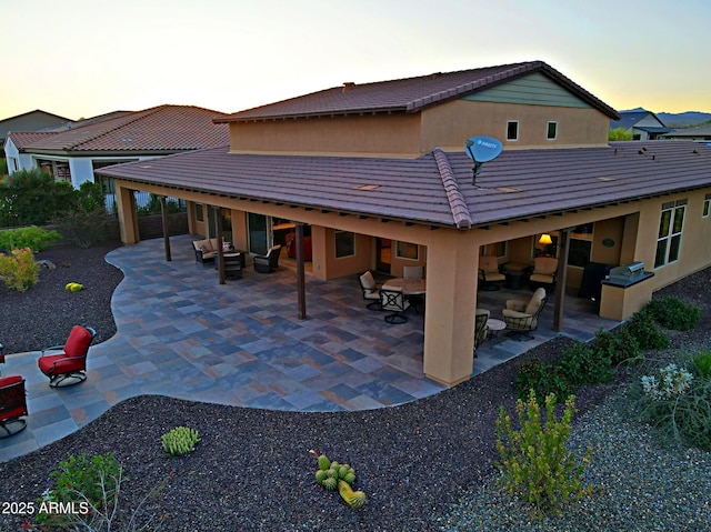 17249 E Fort Verde Rd, Rio Verde, AZ 85263 - back of house at dusk with an outdoor hangout area, a patio, stucco siding, and a tile roof