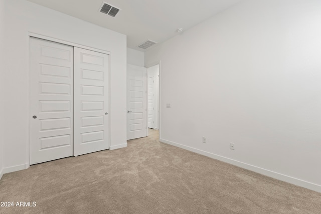 unfurnished bedroom with light colored carpet and a closet