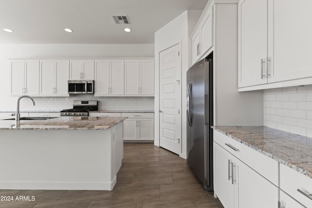 kitchen featuring sink, appliances with stainless steel finishes, light stone countertops, white cabinets, and decorative backsplash