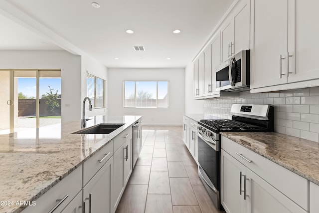 kitchen featuring a wealth of natural light, appliances with stainless steel finishes, sink, and white cabinets