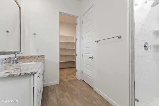 bathroom featuring walk in shower, vanity, and wood-type flooring