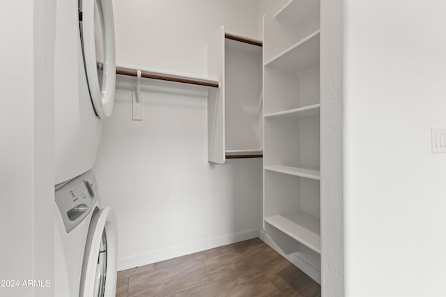 walk in closet with hardwood / wood-style flooring and stacked washer / dryer