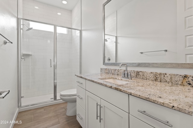 bathroom with an enclosed shower, vanity, hardwood / wood-style flooring, and toilet