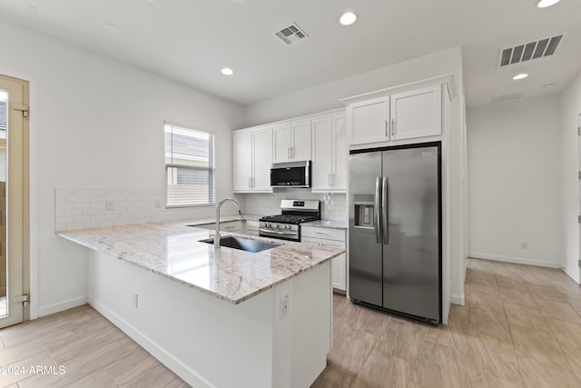 kitchen featuring stainless steel appliances, white cabinetry, sink, and kitchen peninsula