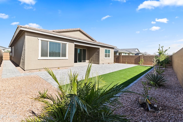 back of house with a patio and a lawn