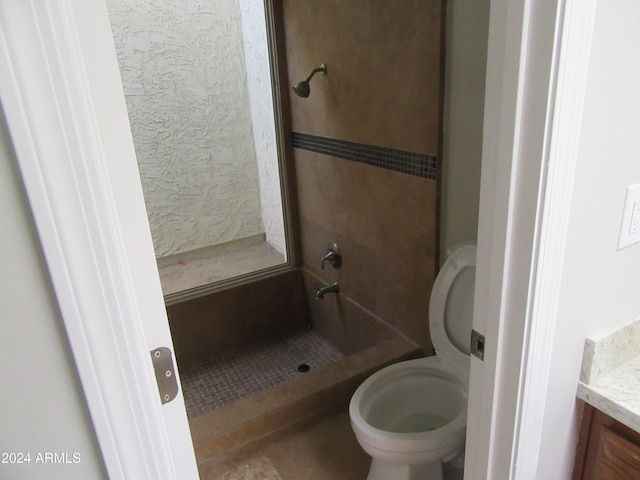 bathroom featuring a tile shower, vanity, and toilet