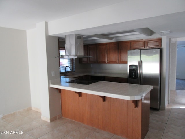 kitchen with exhaust hood, stainless steel fridge, light tile patterned floors, and kitchen peninsula