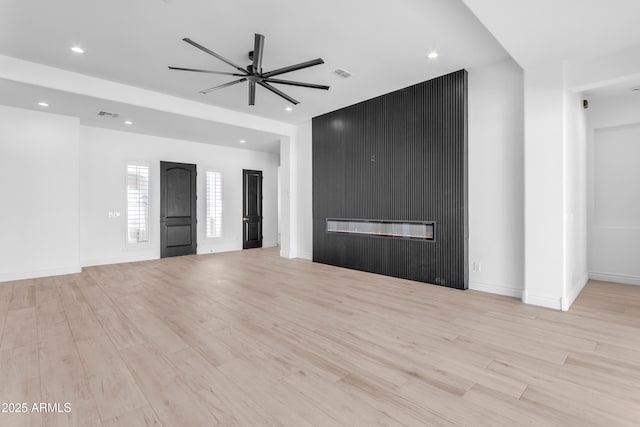 unfurnished living room featuring a ceiling fan, light wood-type flooring, visible vents, and a fireplace