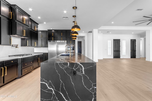 kitchen featuring visible vents, dark stone counters, appliances with stainless steel finishes, light wood-type flooring, and recessed lighting