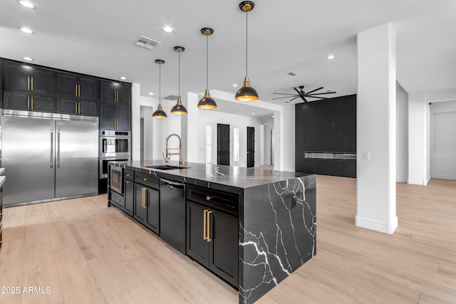 kitchen featuring appliances with stainless steel finishes, dark cabinetry, a sink, and visible vents