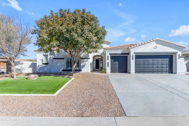 mediterranean / spanish house featuring a garage, concrete driveway, a tiled roof, stucco siding, and a front yard