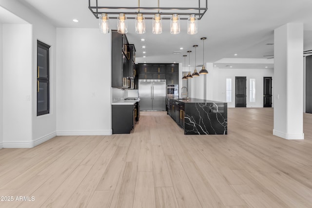 kitchen with stainless steel appliances, recessed lighting, open floor plan, and light wood finished floors