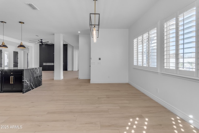 interior space with a ceiling fan, baseboards, visible vents, and light wood finished floors