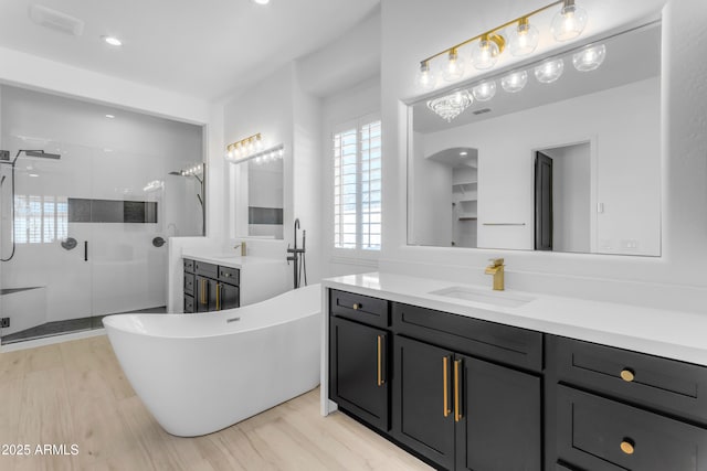 full bath with a soaking tub, a shower stall, vanity, and wood finished floors