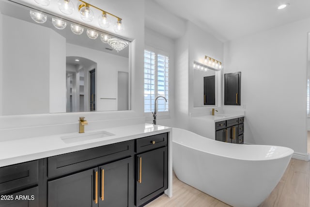 full bath featuring a freestanding tub, recessed lighting, wood finished floors, and vanity