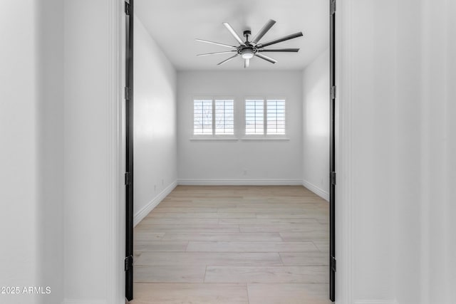 spare room with ceiling fan, light wood-style flooring, and baseboards