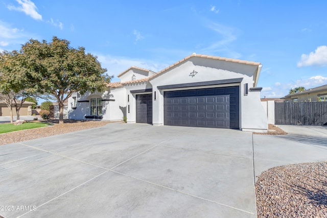 view of front of house with driveway, an attached garage, fence, and stucco siding