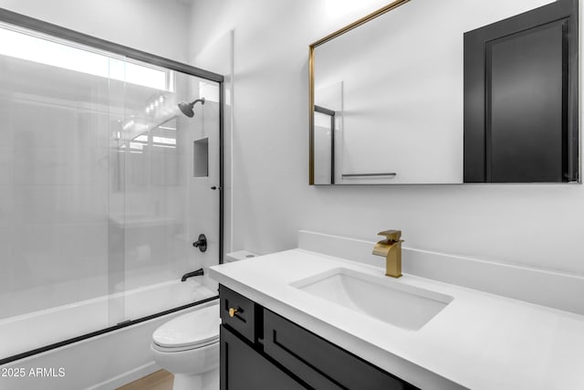 full bath featuring combined bath / shower with glass door, vanity, and toilet