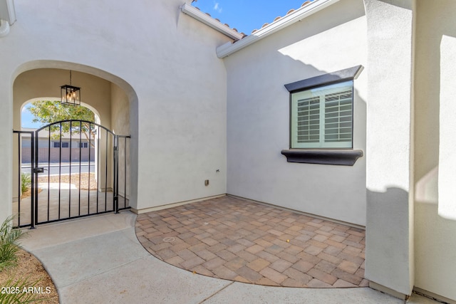 entrance to property featuring a gate, a patio area, and stucco siding