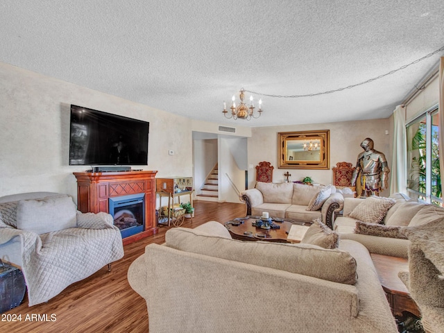 living room featuring wood-type flooring, a textured ceiling, and a chandelier