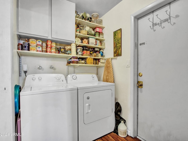 washroom featuring washing machine and clothes dryer, hardwood / wood-style floors, and cabinets