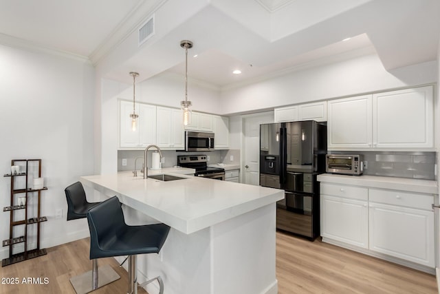 kitchen with decorative light fixtures, a peninsula, stainless steel appliances, light countertops, and white cabinetry