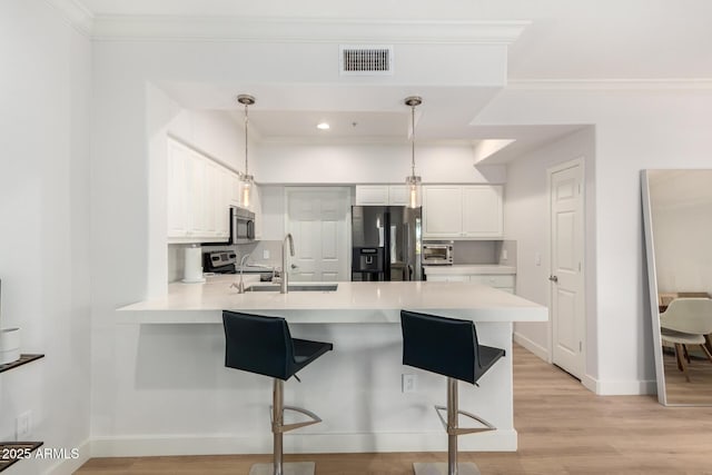 kitchen featuring appliances with stainless steel finishes, light countertops, hanging light fixtures, and a peninsula