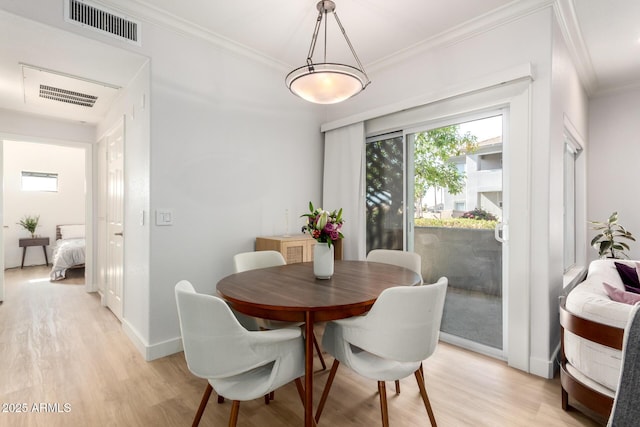 dining area with ornamental molding, visible vents, light wood-style floors, and baseboards