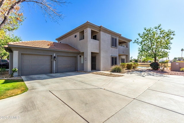 view of front facade featuring a garage, concrete driveway, a tile roof, and stucco siding