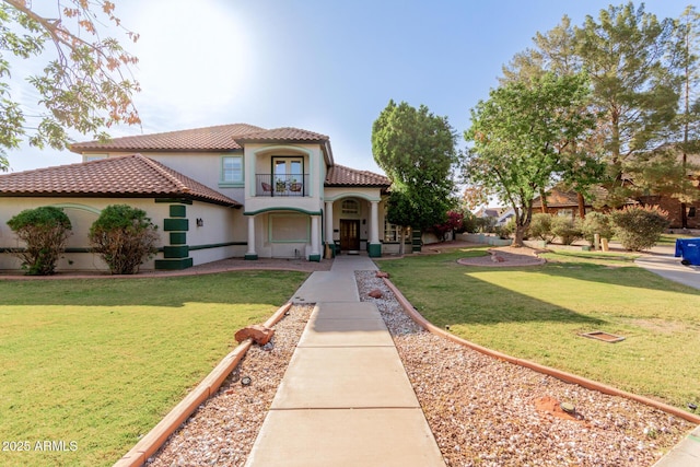 mediterranean / spanish-style house featuring a tile roof, a front yard, and stucco siding