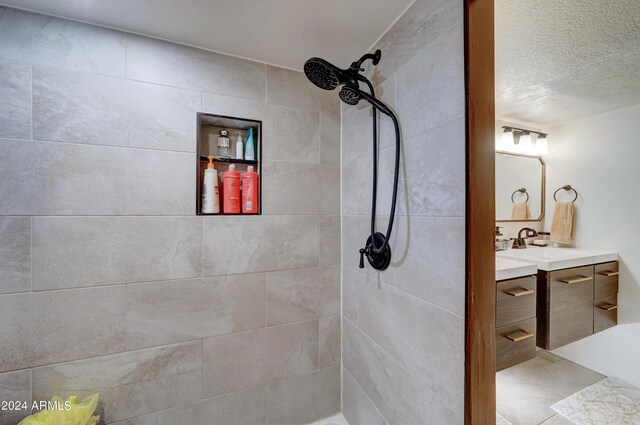 bathroom featuring tile patterned flooring, dual vanity, and a textured ceiling