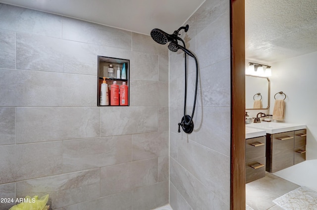 bathroom featuring tiled shower, vanity, and a textured ceiling